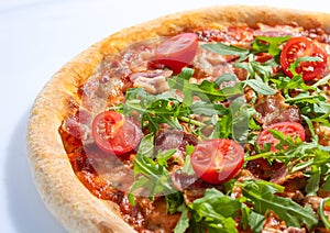 Italian hot pizza with tomato, arugula and pieces of bÐ°Ñon isolated on white background